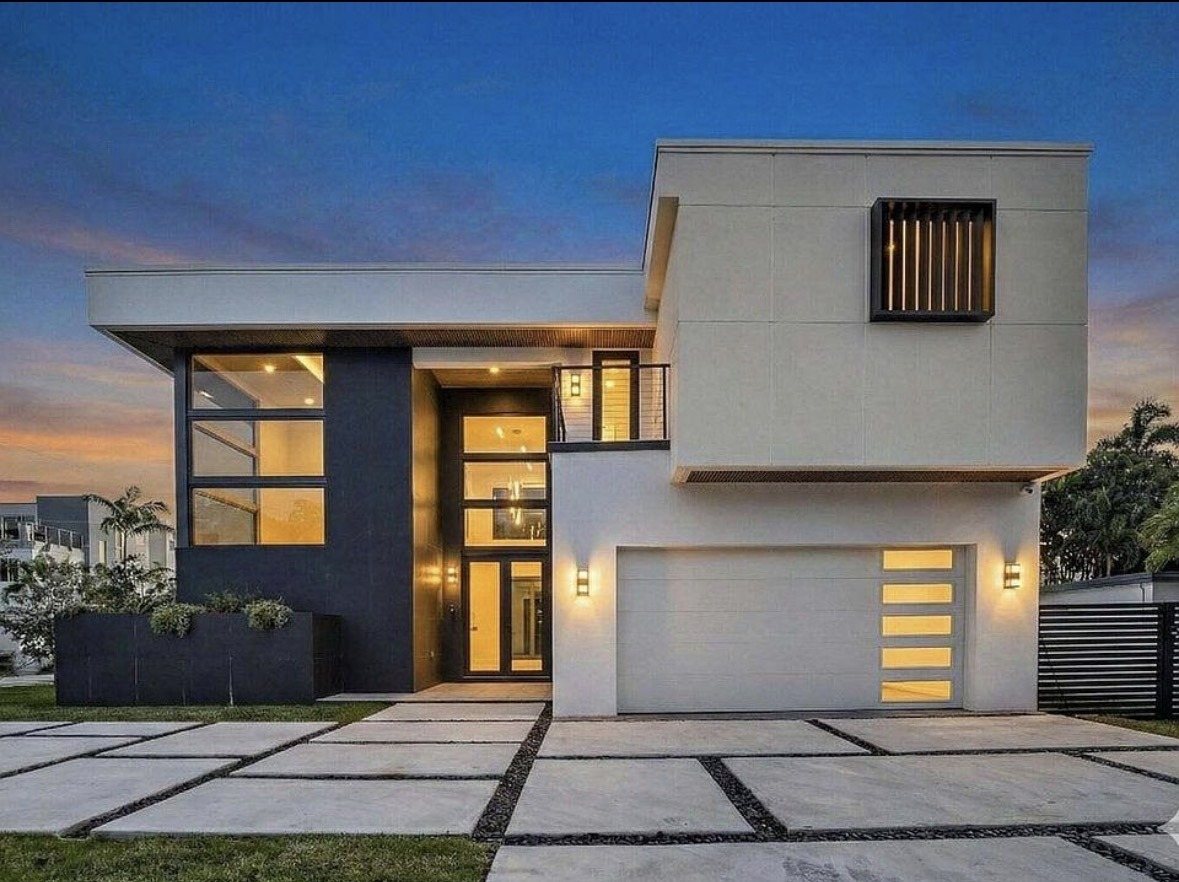 The client's modern two-story house exterior at dusk, porch and interior lights, landscaped walkway leading to the door